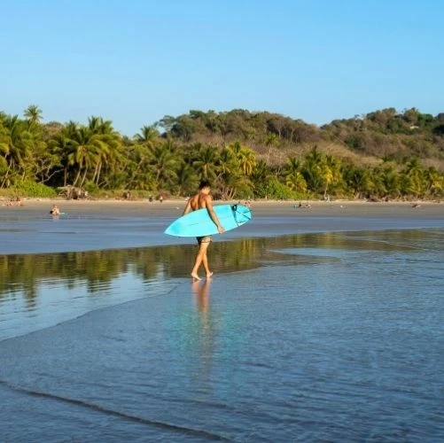 Surfeur marchant sur la magnifique plage de Playa Hermosa à Santa Teresa, au Costa Rica.