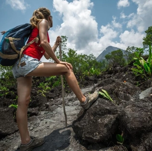 Une randonneuse sur un sentier de l'Arenal au Costa Rica, regardant le volcan à l'horizon